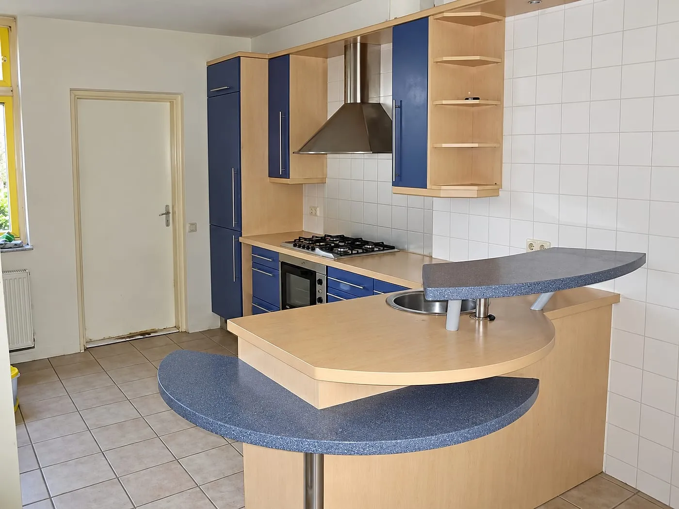 Blauwe hoekkeuken met halfronde bars en witte wandtegels vóór de renovatie — keukenrenovatie in Groningen door Bontbouw