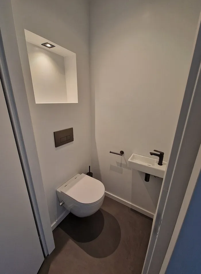 Gerenoveerd toilet in Groningen met een verlichte nis, hangtoilet en fonteintje